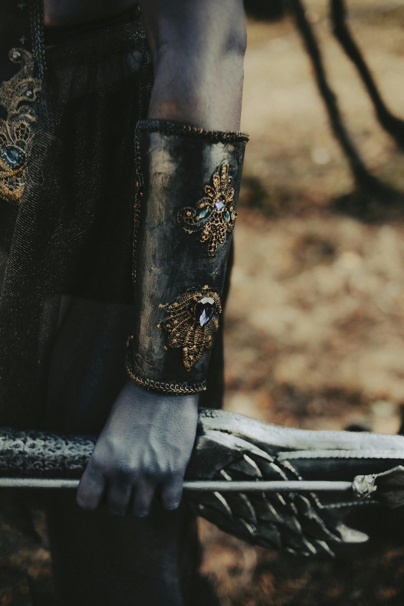 A detailed close-up of a hand in ornate armor holding a medieval-style bow.