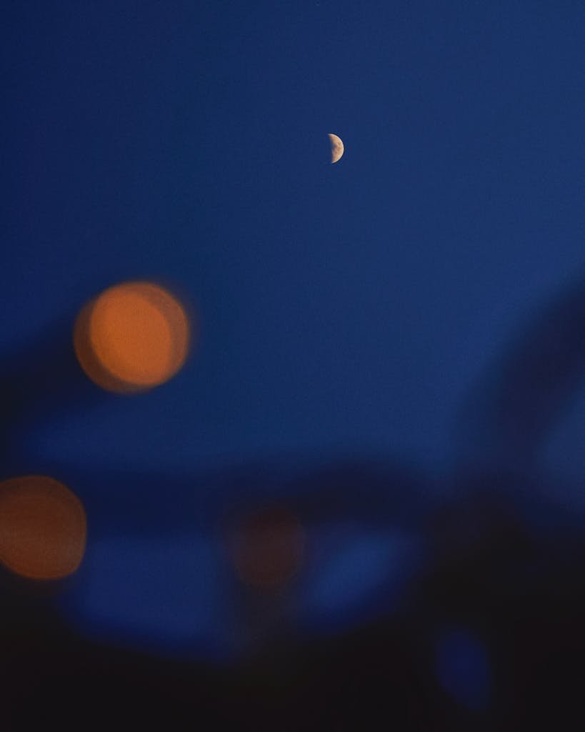 A serene night sky with a crescent moon and glowing bokeh lights creating a mystical ambiance.
