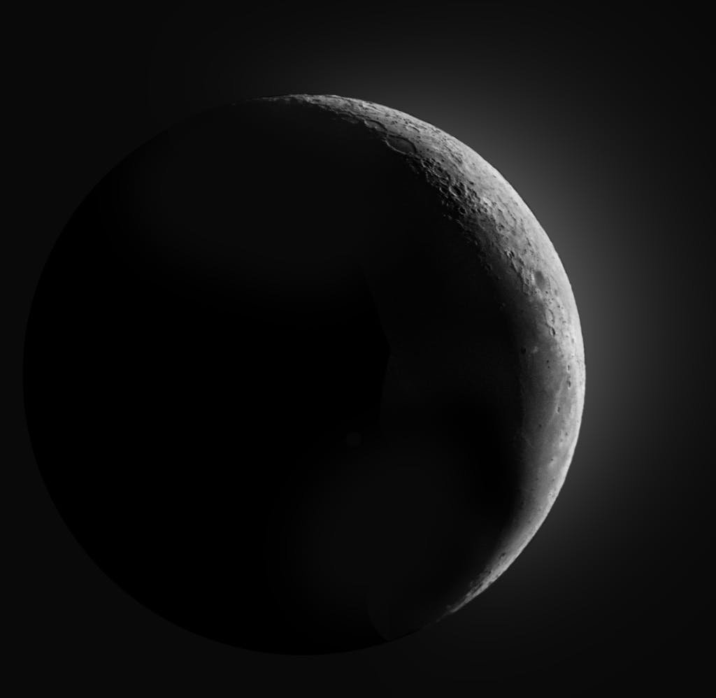 A striking crescent moon shines brightly in the dark night sky, captured with stunning detail.