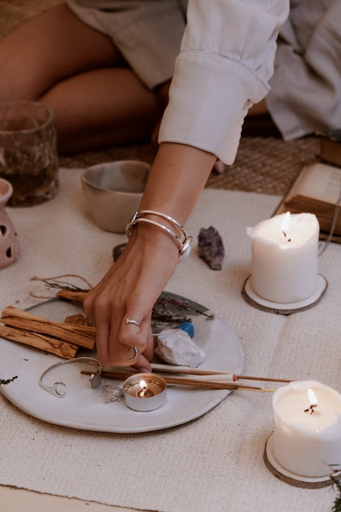 Woman setting up a peaceful meditation space with candles, incense, and crystals.